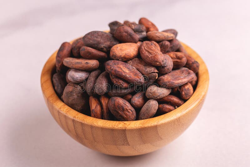 Bowl full of aromatic raw cocoa beans. On gray marble background. Horizontal view. Copy space stock image