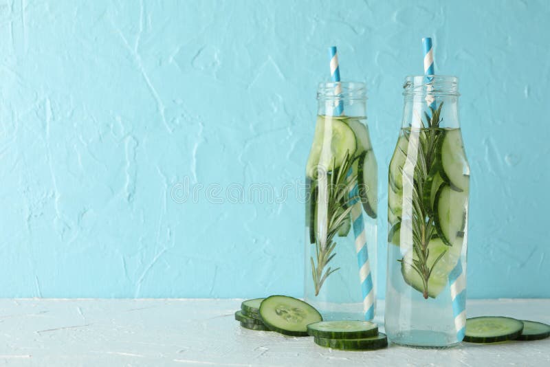 Composition with bottles of cucumber water against background, space for text. Composition with bottles of cucumber water against blue background, space for text stock photography