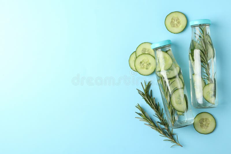 Composition with bottles of cucumber water on background, space for text. Composition with bottles of cucumber water on blue background, space for text stock photo
